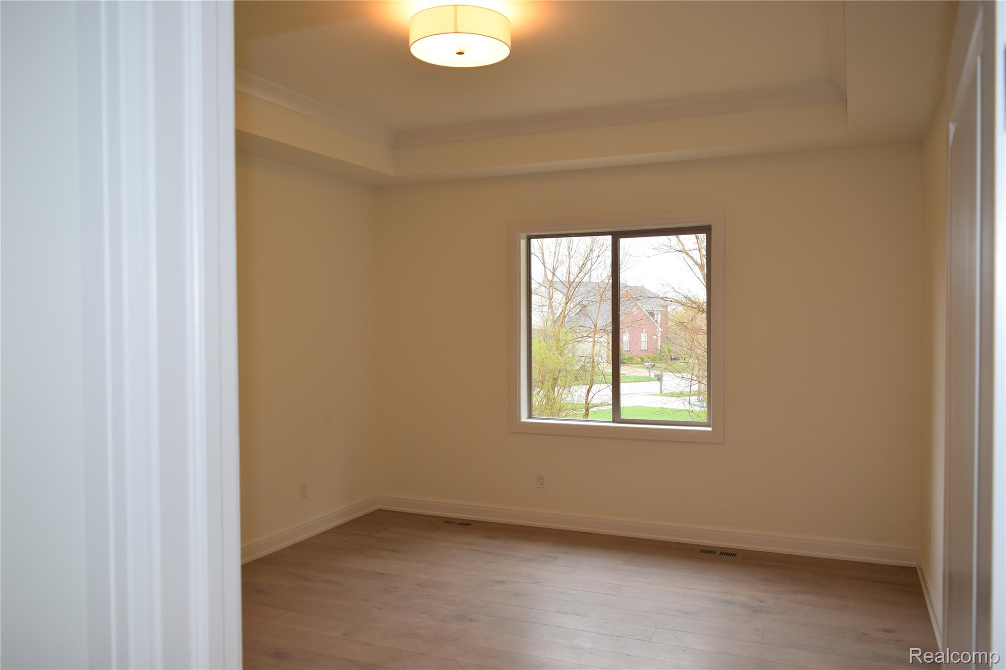 3093 Raffler Drive Rochester, MI 48307 - Photo 24 of 34 Unfurnished Primary Suite with a raised ceiling, light wood flooring, and crown molding