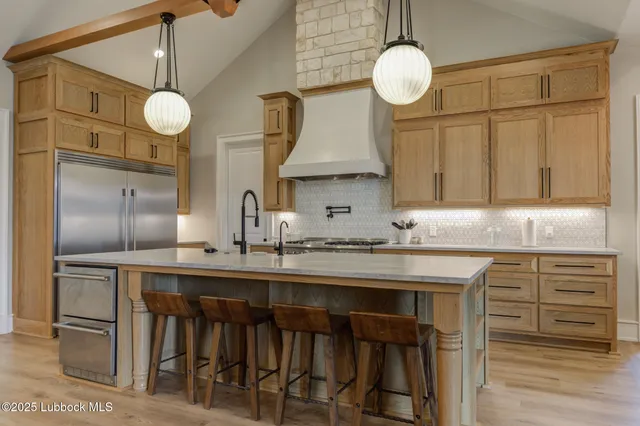 a large kitchen with stainless steel appliances granite countertop a stove a sink a dining table and chairs with wooden floor