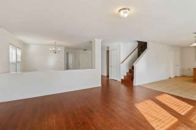 a view of an empty room with wooden floor and a kitchen