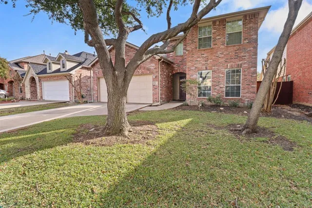 a tree in front of a house with a yard