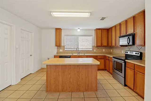 a kitchen with stainless steel appliances granite countertop a stove a sink and a microwave