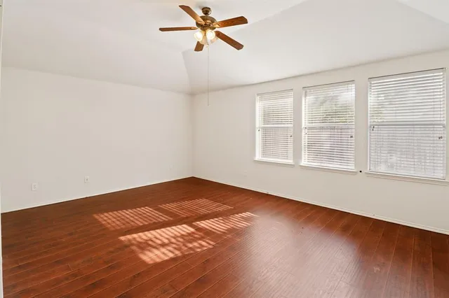 a view of empty room with wooden floor and fan