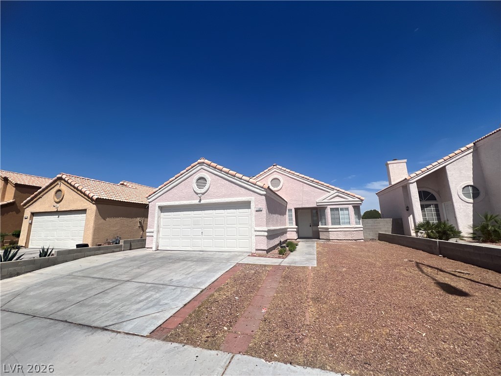 1309 Goldenglow Road Las Vegas, NV 89108 - Photo 2 of 11 A classic facade with an attached garage and a minimal-maintenance yard under a vast blue sky.