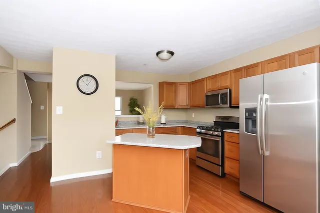 a kitchen with stainless steel appliances a refrigerator a sink a stove and white cabinets with wooden floor