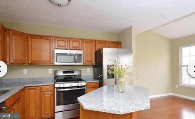 a kitchen with stainless steel appliances granite countertop a sink refrigerator stove and microwave