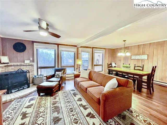 a living room with furniture a rug and a floor to ceiling window