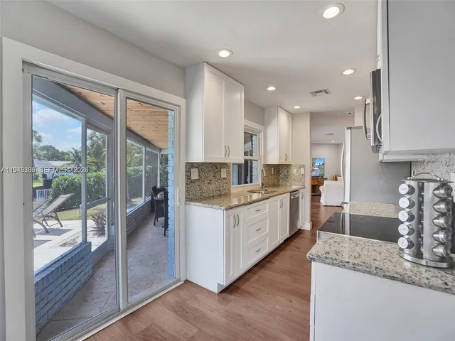 a kitchen with granite countertop a stove a sink and a refrigerator