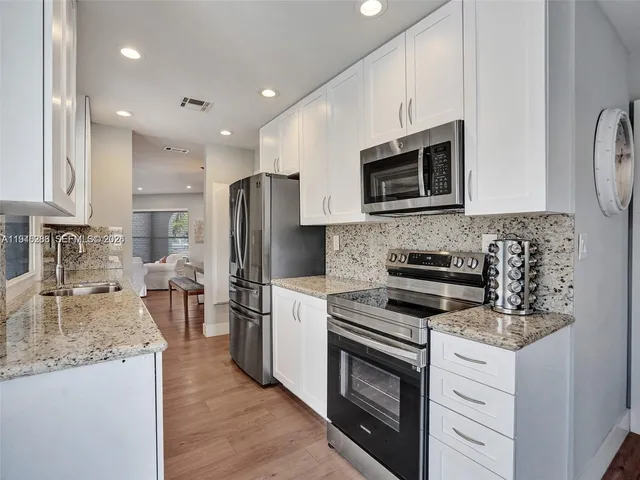 a kitchen with stainless steel appliances granite countertop a stove microwave sink and refrigerator