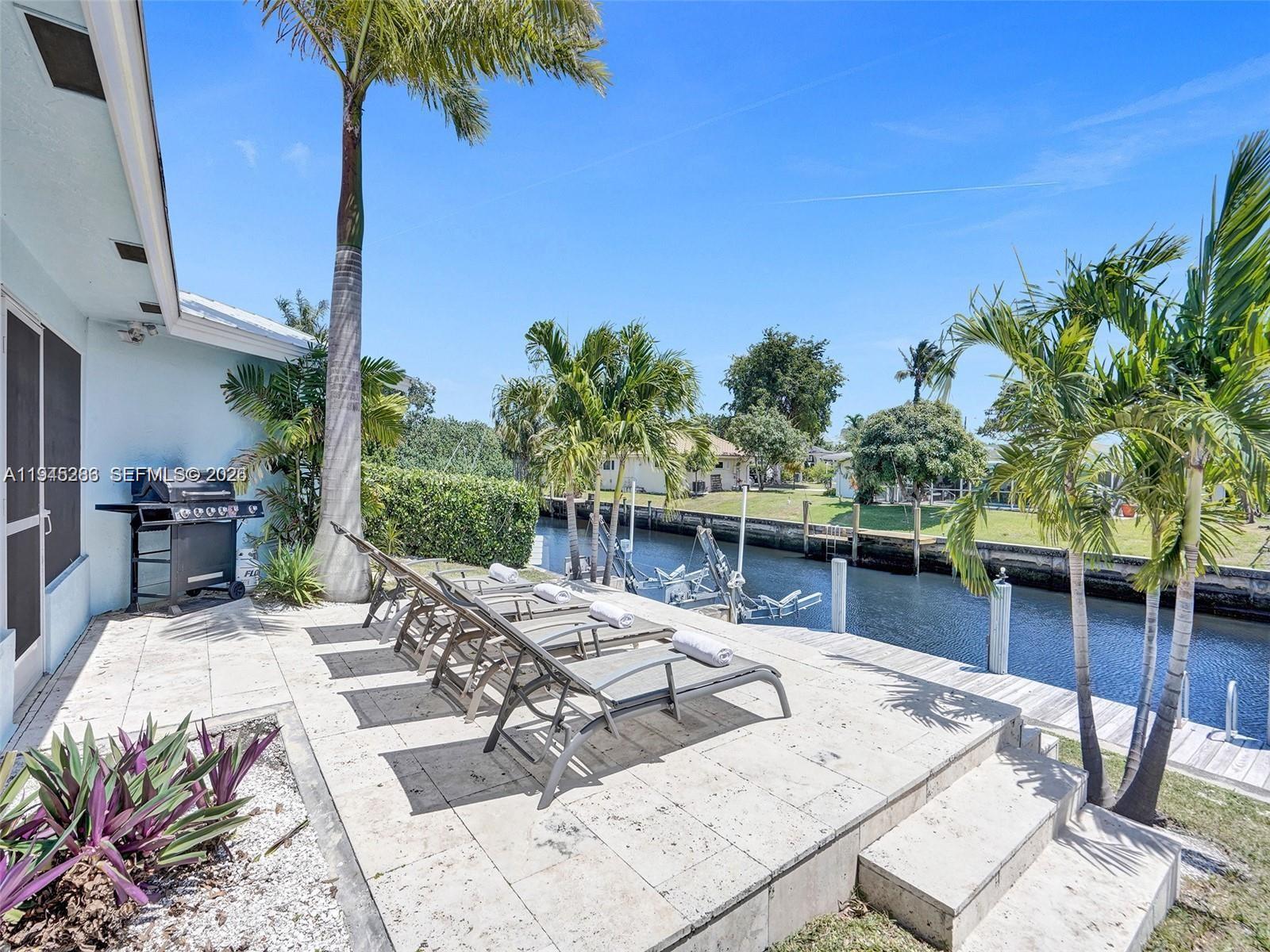 620 West Palmetto Park Road Boca Raton, FL 33486 - Photo 2 of 38 a view of a patio with couches table and chairs with potted plants and large tree