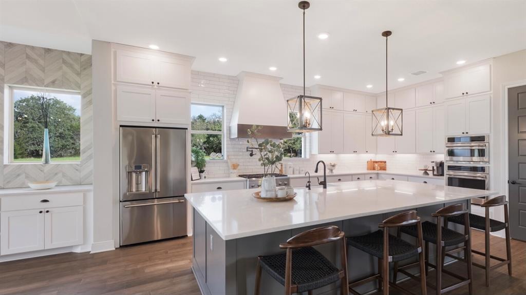 Lot 12 Ridgeway Trail Johnson City, TX 78636 - Photo 3 of 26 a kitchen with stainless steel appliances granite countertop a sink a stove a refrigerator and island with wooden floor