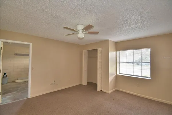 an empty room with windows and fan