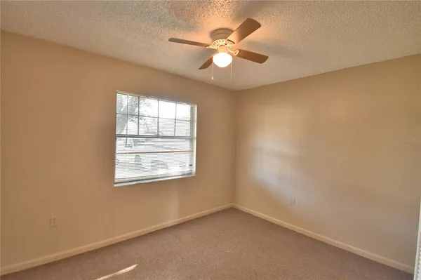 an empty room with a window and a fan