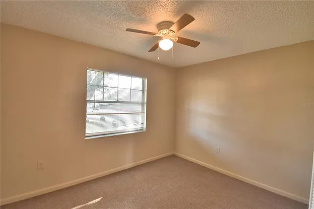 an empty room with a window and a fan