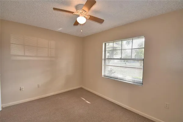an empty room with a window and a fan