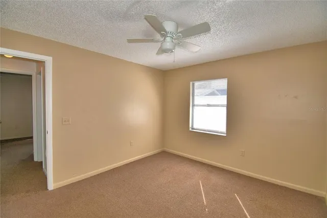 an empty room with a window and a ceiling fan