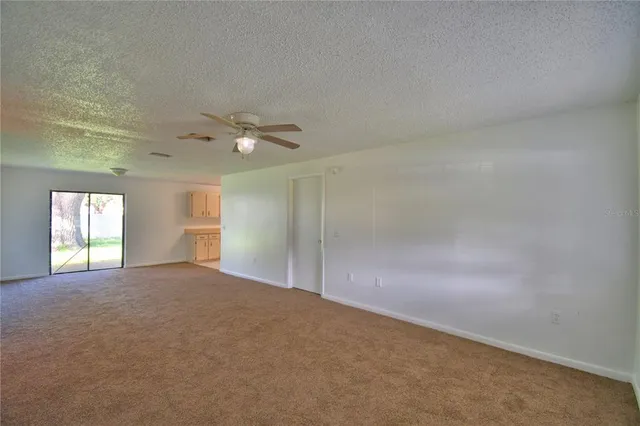 an empty room with windows and ceiling fan view