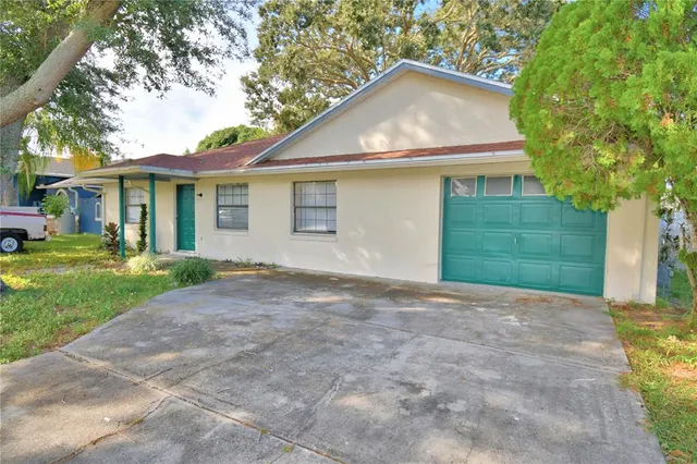 a view of a white house next to a yard and a large tree