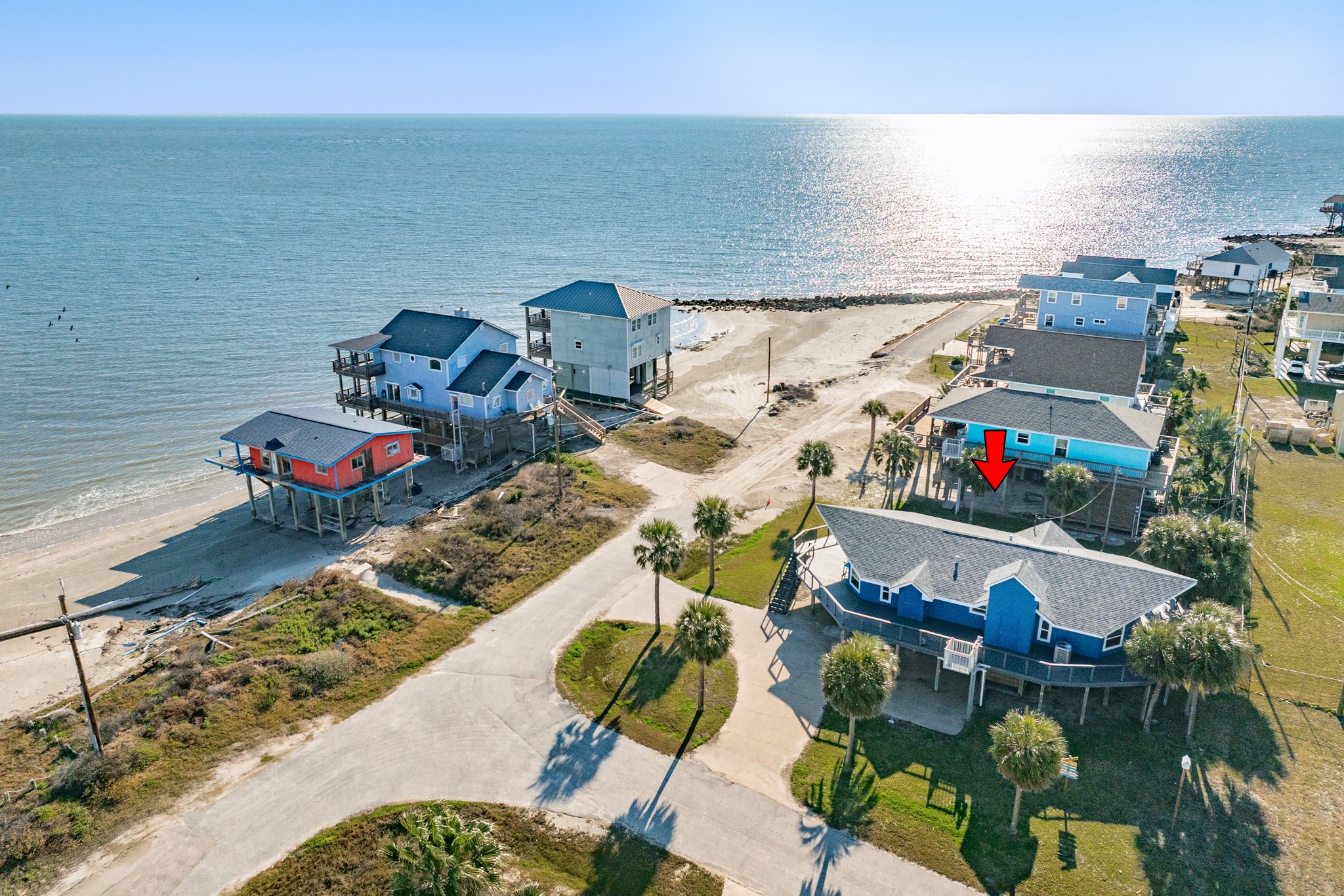 Aerial – Beachside Setting – Aerial view showcasing the home’s location near the shoreline with surrounding coastal residences and open water views nearby.