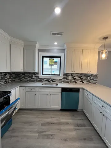 a large white kitchen with granite top and stainless steel appliances