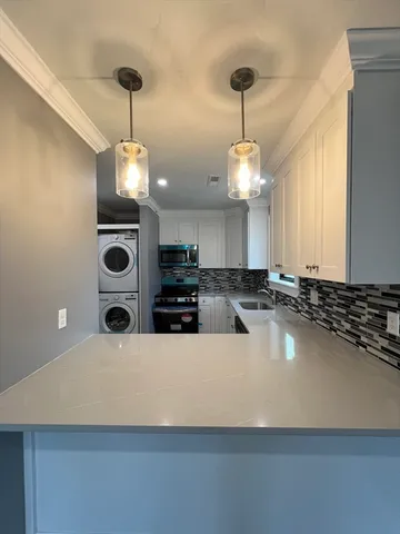 a large white kitchen with a large center island and stainless steel appliances