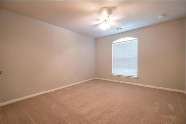 an empty room with a chandelier fan and windows