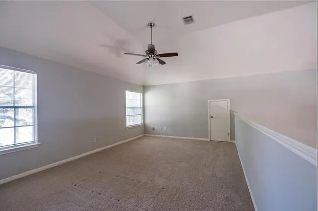 an empty room with windows and fan