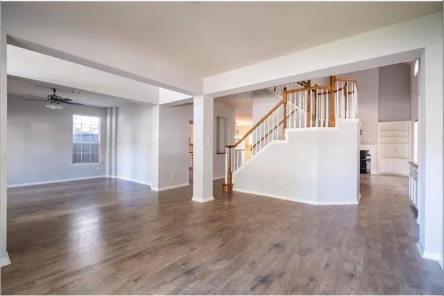 a view of a livingroom with wooden floor and stairs