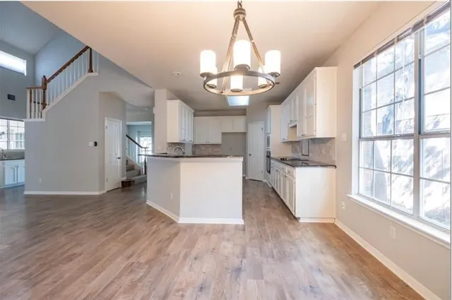 a kitchen with stainless steel appliances granite countertop wooden floors and white cabinets