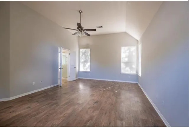 an empty room with windows and fan