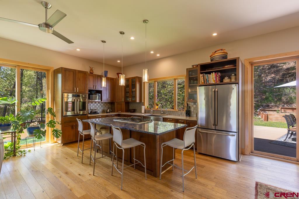 7041 County Road 203 Durango, CO 81301 - Photo 17 of 45 a kitchen with stainless steel appliances granite countertop a refrigerator a stove a sink a dining table and chairs with wooden floor