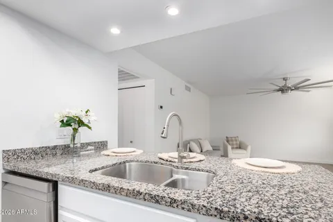 an empty room with chandelier fan and windows