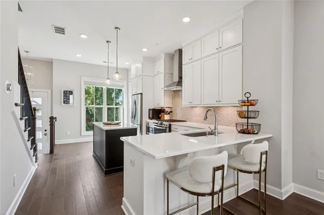 a kitchen with stainless steel appliances granite countertop a stove a sink a refrigerator and a dining table with wooden floor