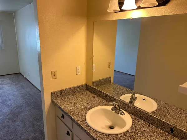 a bathroom with a granite countertop sink and a mirror