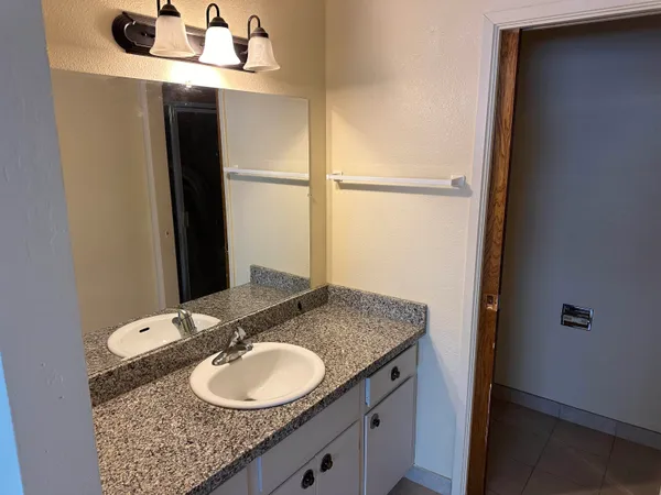 a bathroom with a granite countertop sink and a mirror