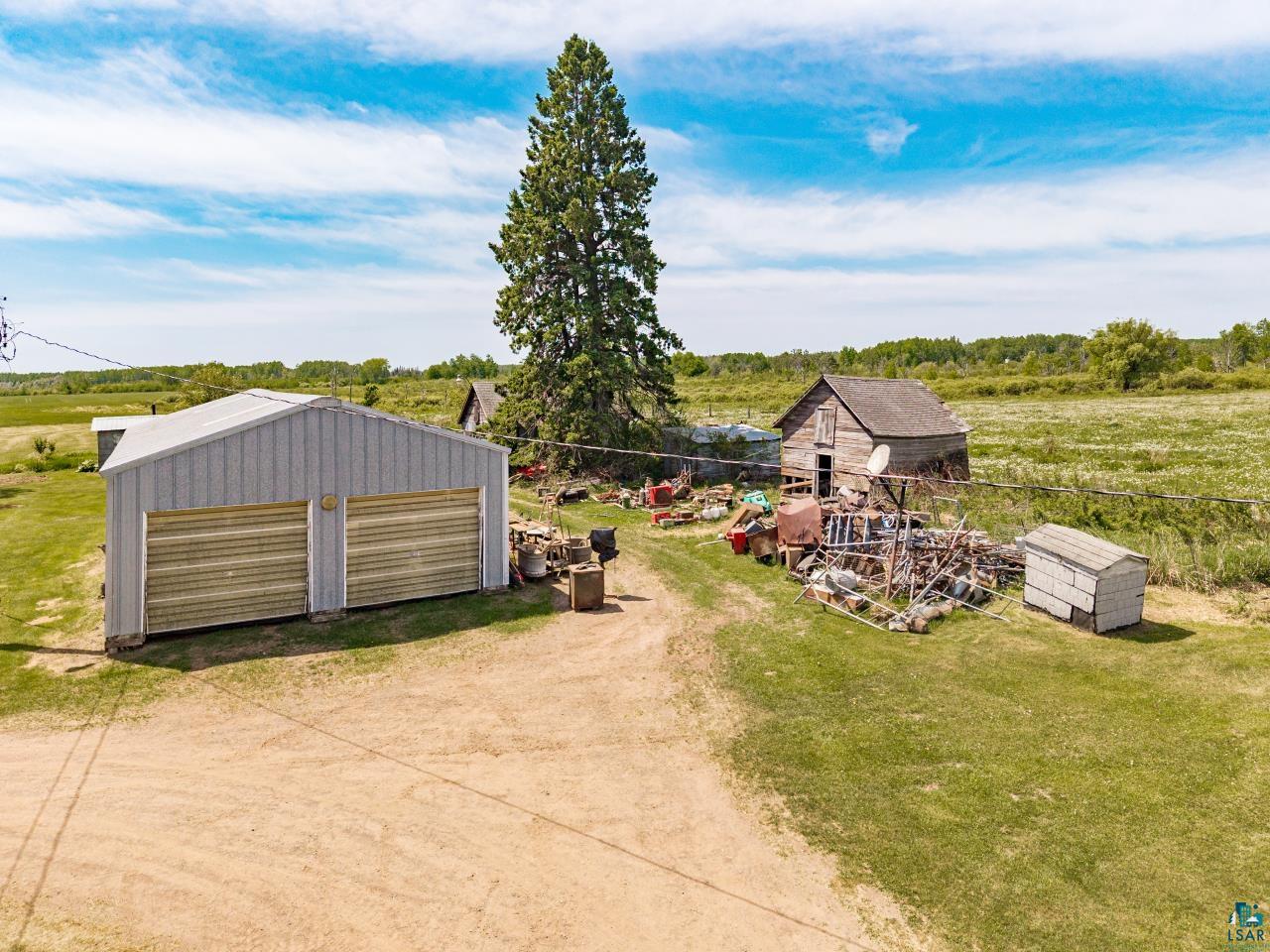 6606 Metso Road Kettle River, MN 55757 - Photo 40 of 84 Metal two-car garage with corrugated paneling and roll-up doors, accompanied by a smaller storage shed