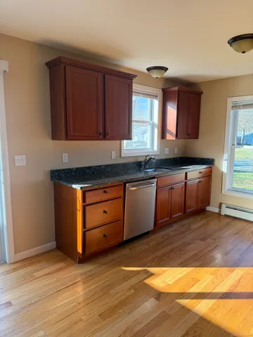 a kitchen with stainless steel appliances granite countertop a sink and cabinets with wooden floor