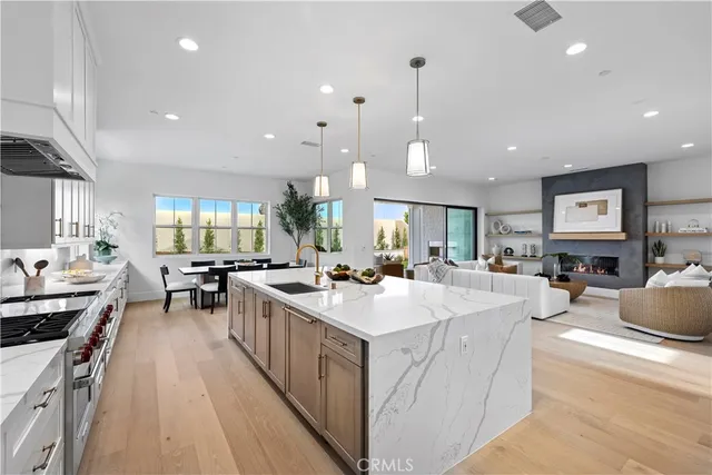 a kitchen with granite countertop a stove a sink a refrigerator and white cabinets with wooden floor