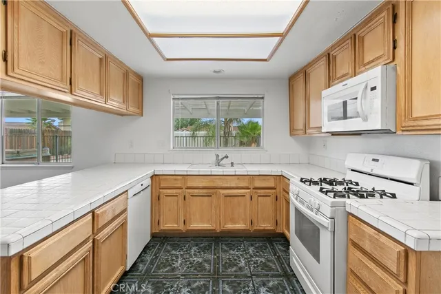 a kitchen with stainless steel appliances granite countertop a sink a stove a microwave cabinets and a window