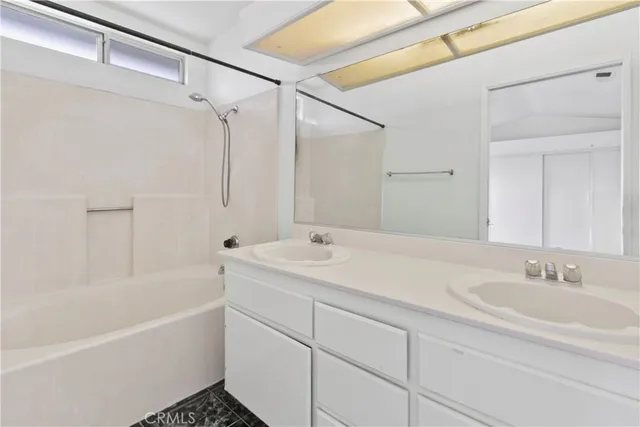 a bathroom with a sink double vanity granite tub shower and a mirror