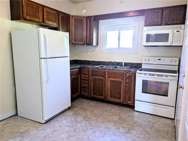 a kitchen with stainless steel appliances granite countertop a refrigerator a stove a sink and a microwave