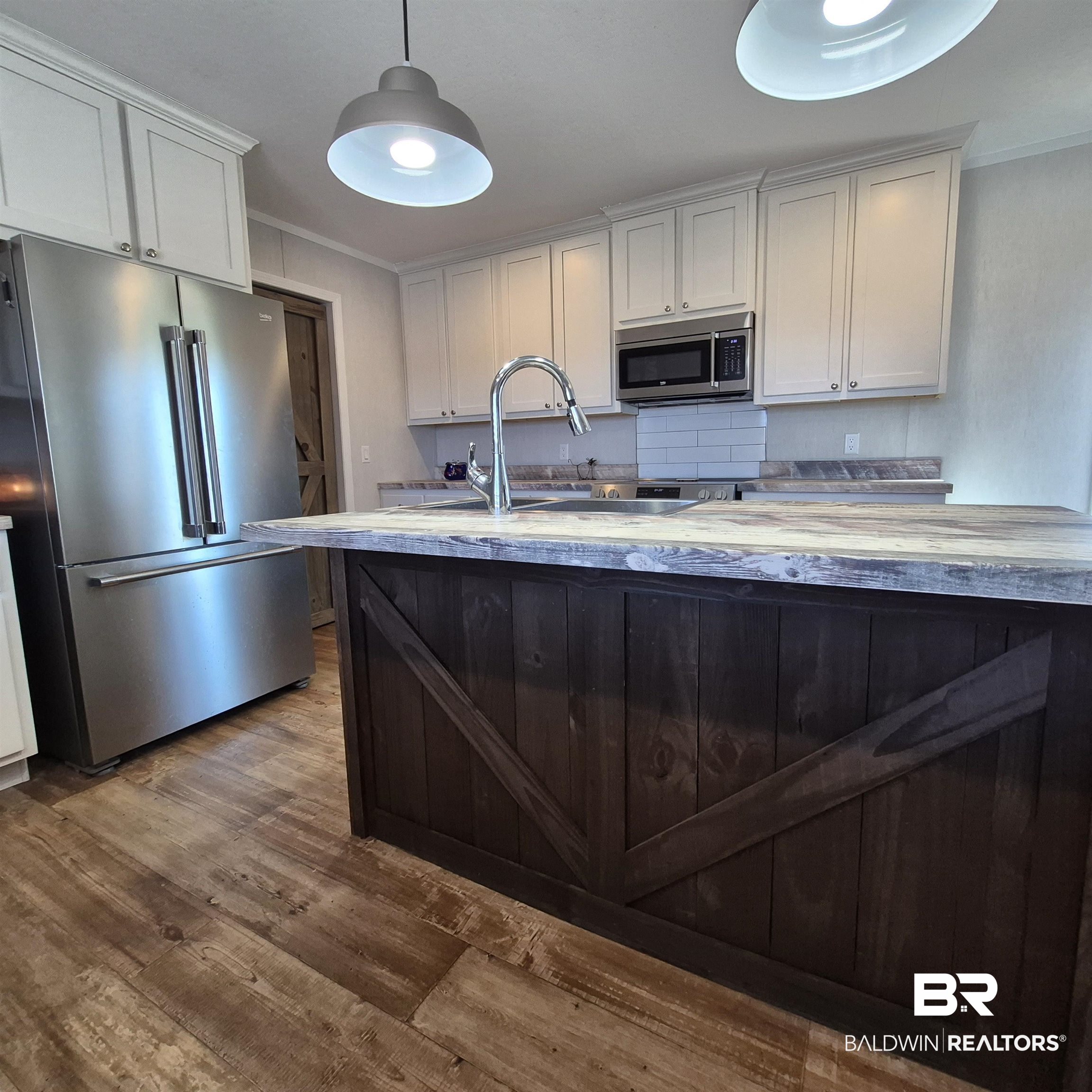 8867 Old Stage Road Repton, AL 36475 - Photo 10 of 37 Kitchen featuring appliances with stainless steel finishes, white cabinetry, dark brown cabinets, dark wood finished floors, and crown molding
