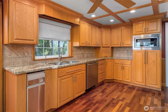 a kitchen with granite countertop stainless steel appliances a sink window and cabinets