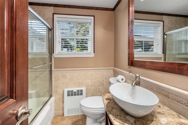 a bathroom with a granite countertop toilet a sink and a large mirror