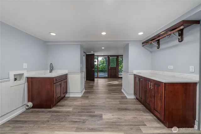 a kitchen with stainless steel appliances granite countertop a sink wooden cabinets and wooden floors