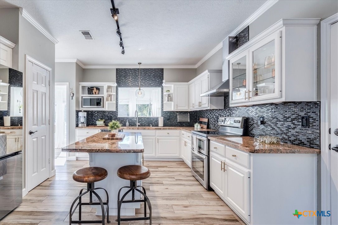 171 Pin Oak Crossing Elgin, TX 78621 - Photo 12 of 38 a kitchen with stainless steel appliances kitchen island granite countertop lots of counter top space and wooden floor