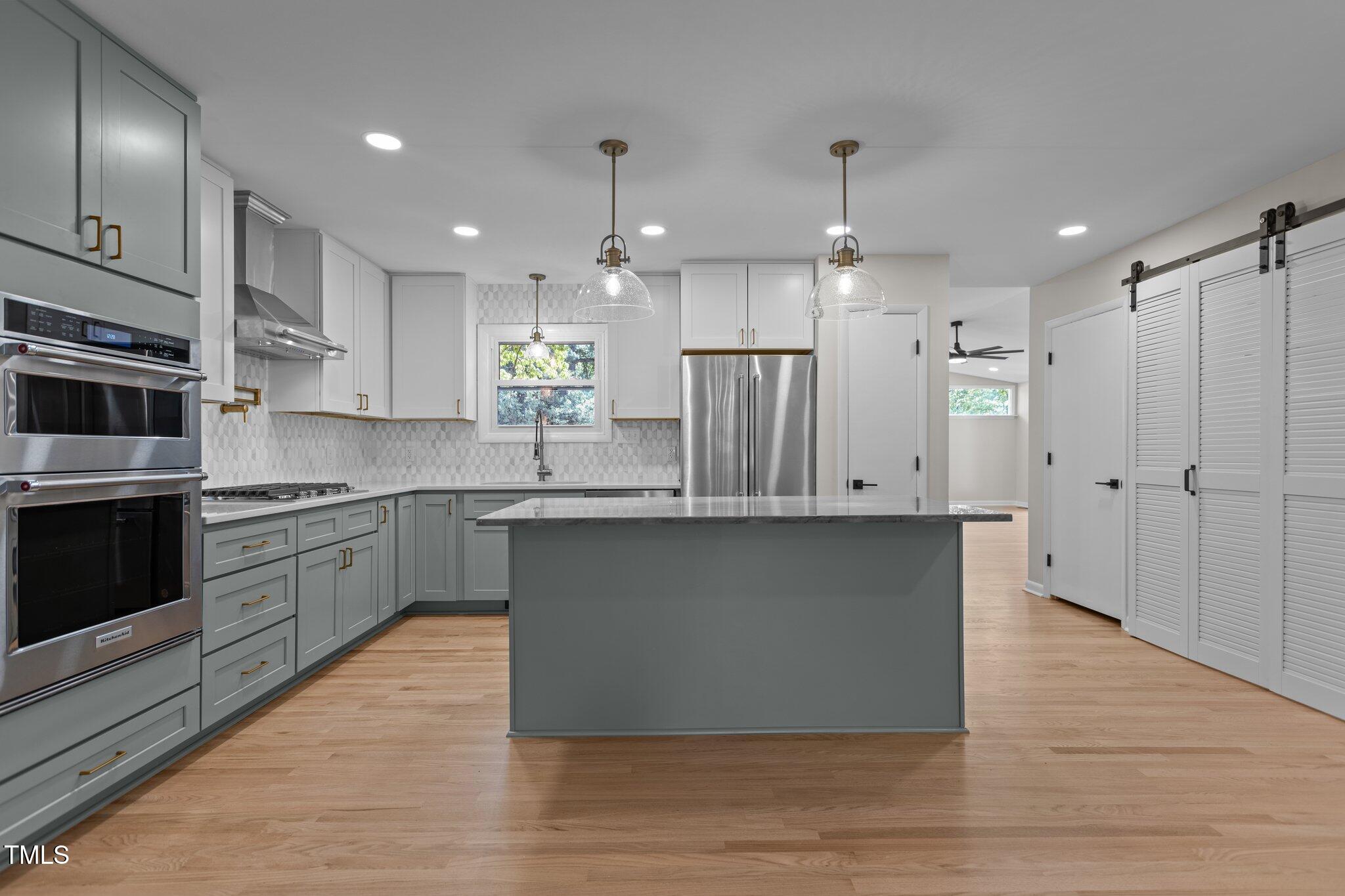 2505 Catalina Court Raleigh, NC 27607 - Photo 4 of 25 a kitchen with stainless steel appliances granite countertop a refrigerator a sink a stove and white cabinets with wooden floor