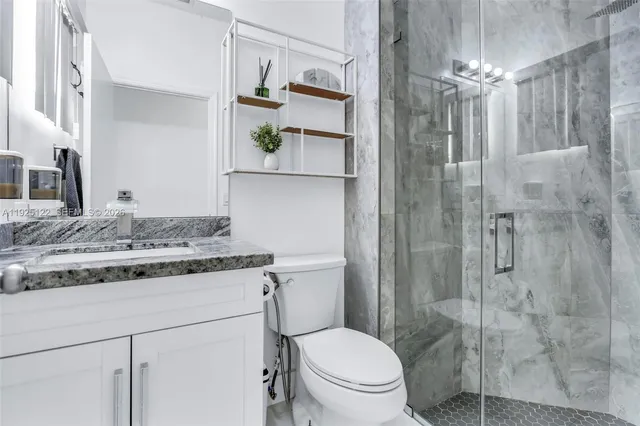 a bathroom with a granite countertop sink a toilet and shower