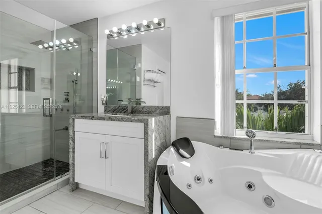 a bathroom with a tub a sink and a large mirror