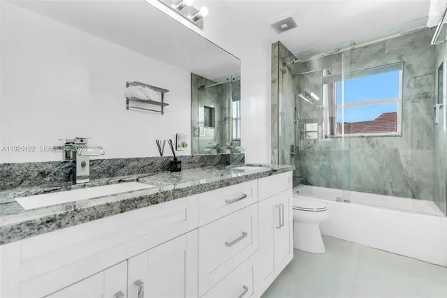 a bathroom with a granite countertop sink mirror toilet and bathtub