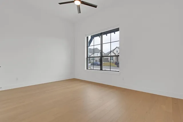 an empty room with windows and fan
